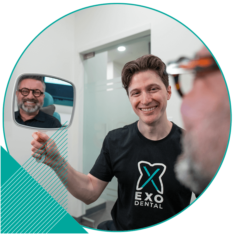 Doctor holding up mirror for patient so they can see their new smile