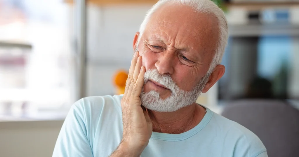 Patient applying a cold compress at home during dental implant recovery