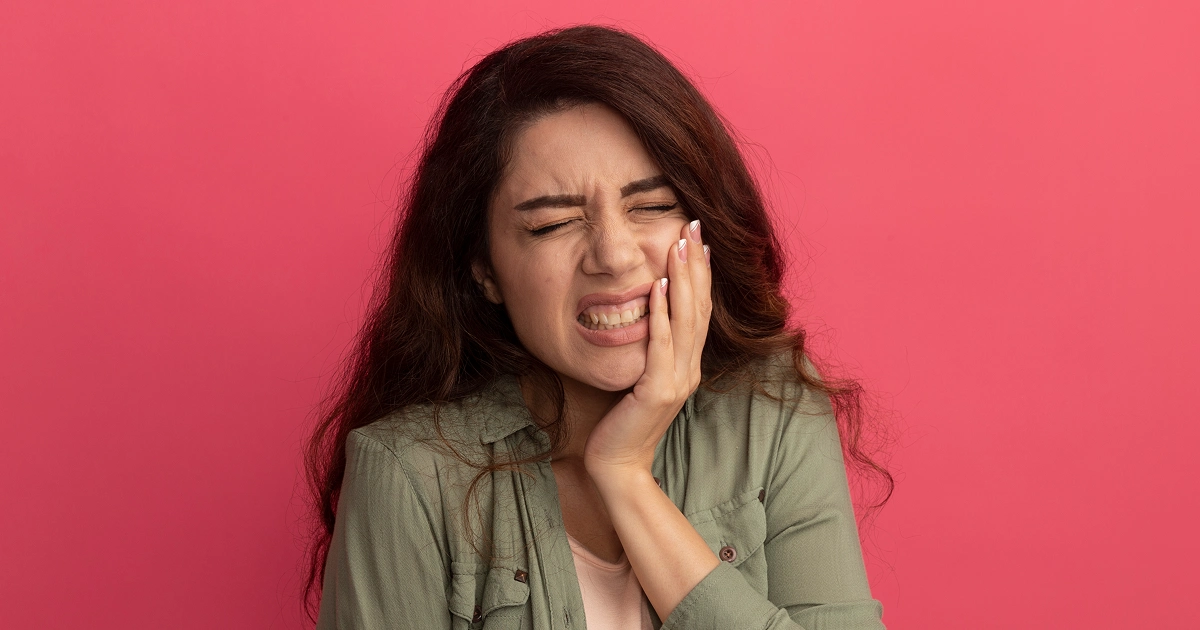 Person holding their cheek with a toothache at night.